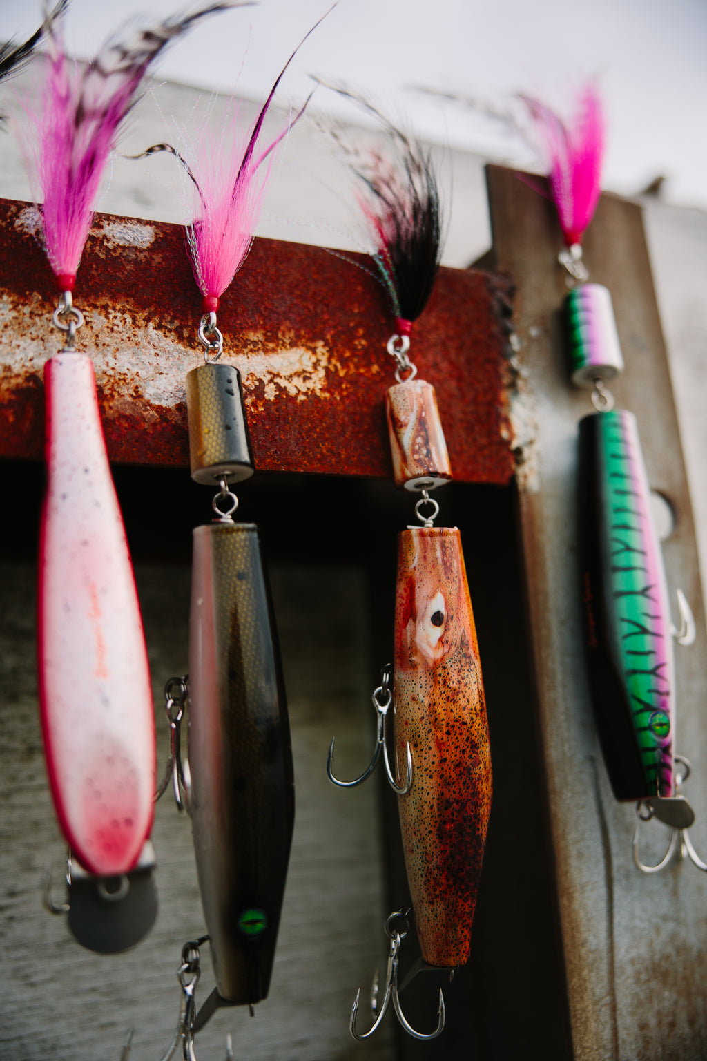 Collection of jointed fishing lures on a rusty metal beam.