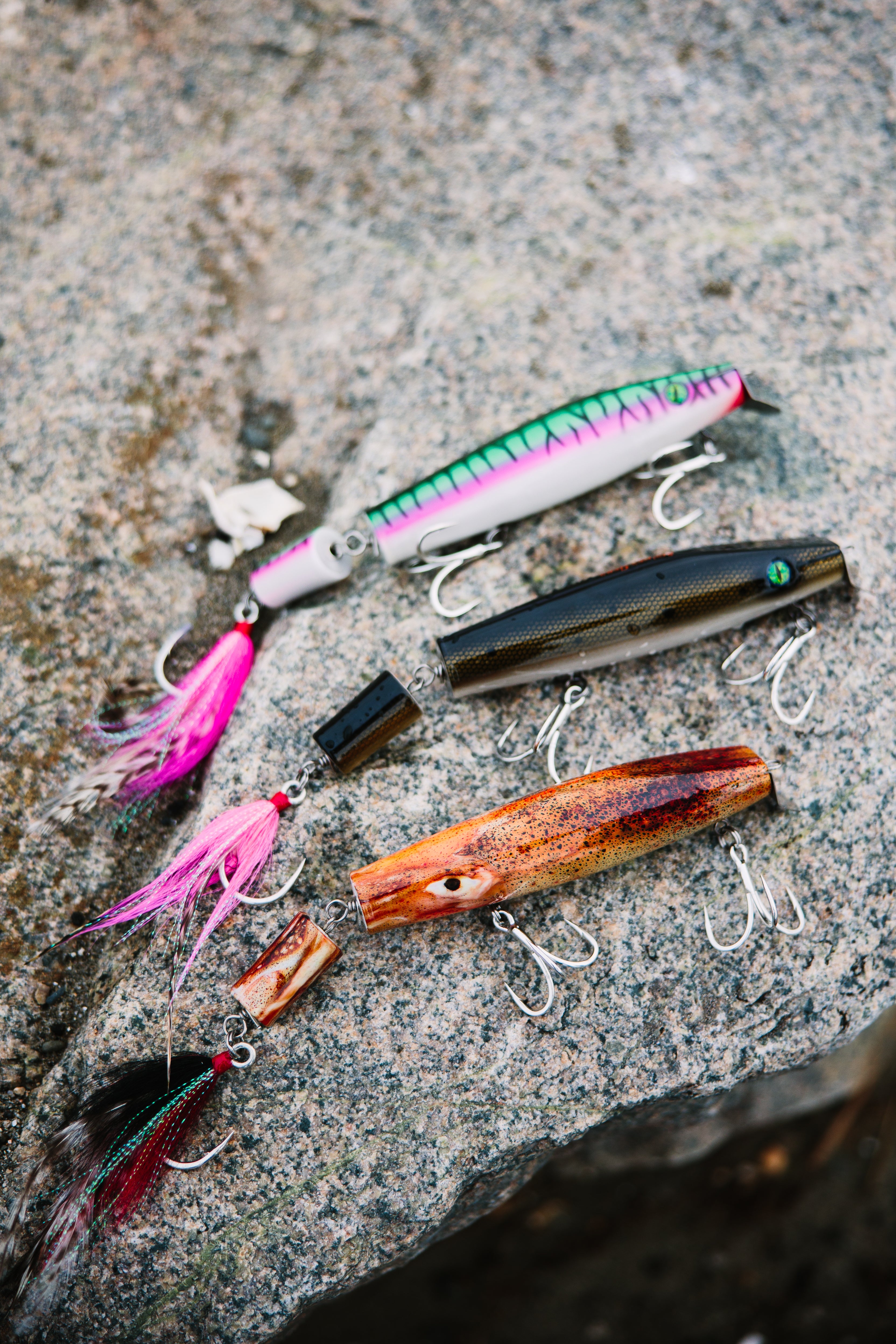 Assorted jointed fishing lures on a textured stone surface